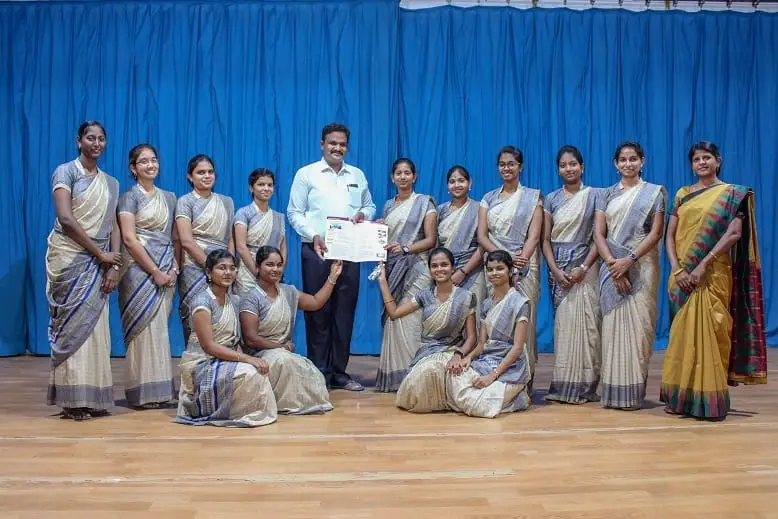 Students and faculty pose for a group photo in front of a blue curtain.