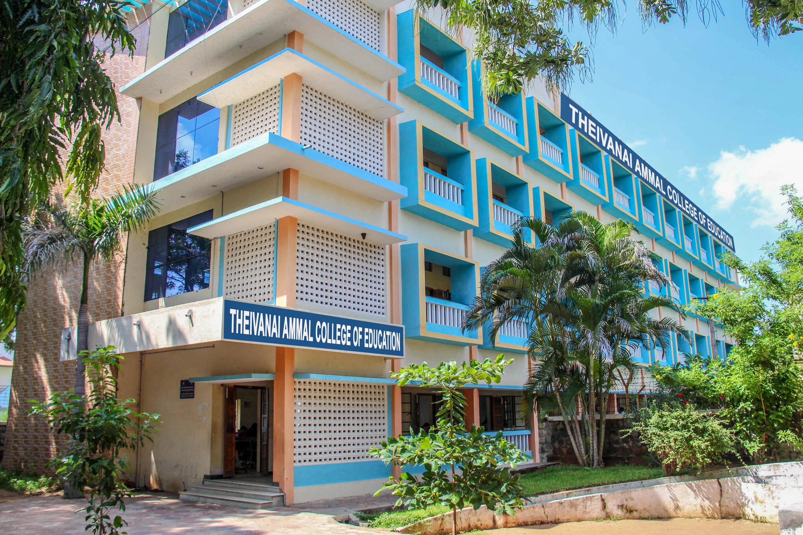 The college’s four-storey building, painted cream and sky blue, with its name board above the entrance and palm trees in front.