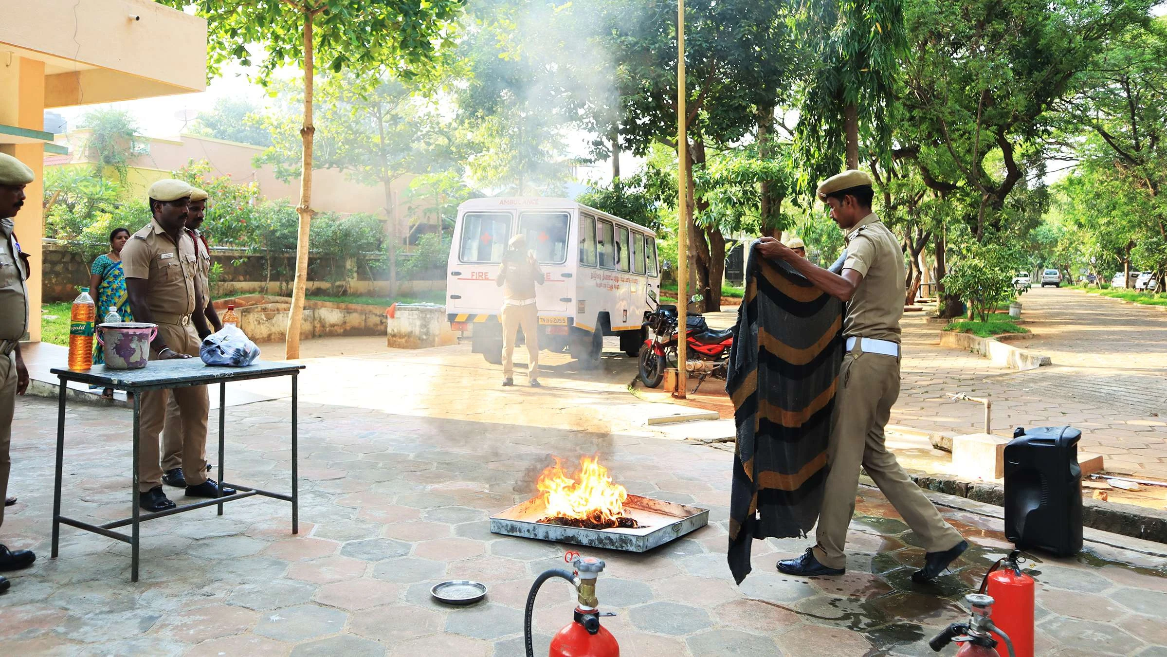 Fire service officers show students how to put out a fire, outdoors.